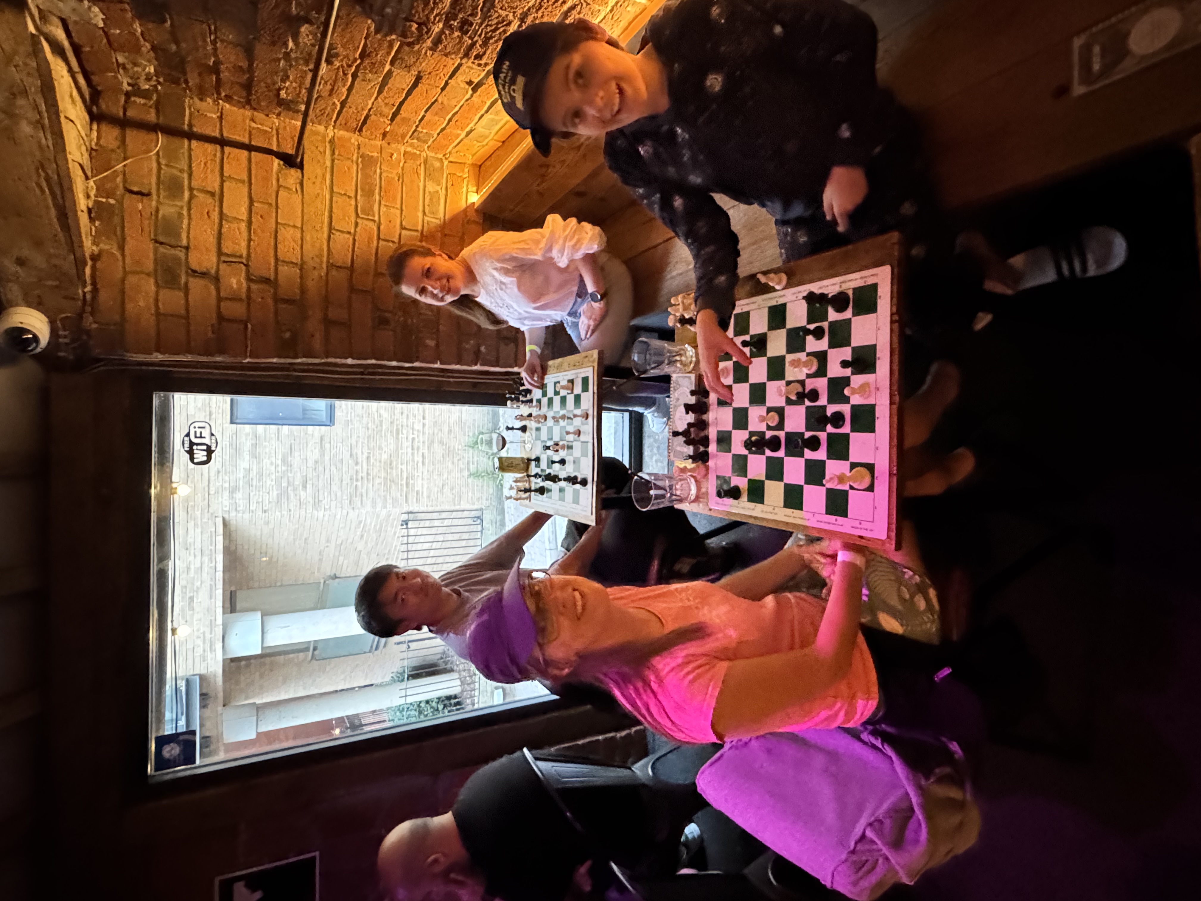 Four players smiling across two chess boards at a Social Chess evening